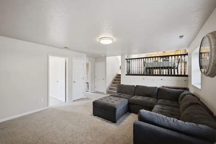 Spacious basement recreation room featuring neutral carpet flooring, recessed ceiling lighting, and extensive wall space