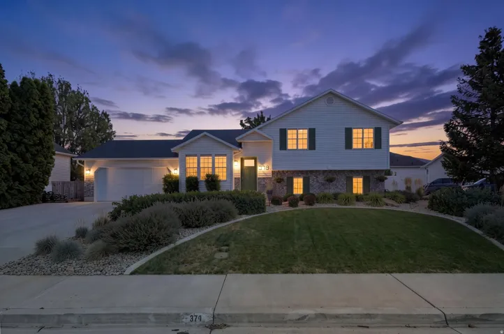 Siding exterior with stone accents, attached garage, and manicured landscaping