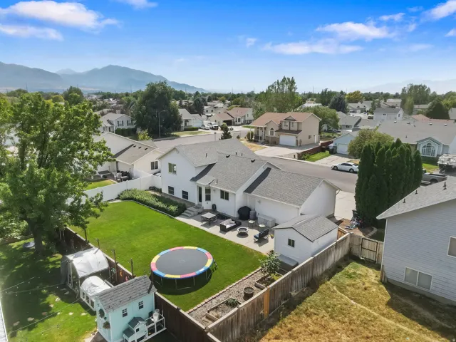 Expansive backyard featuring a manicured lawn, paved patio area, and mature trees