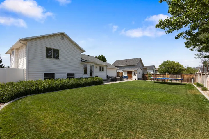 Expansive backyard featuring a manicured lawn, established landscaping, and a privacy fence