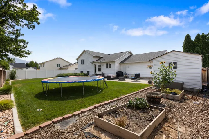 Expansive backyard featuring a manicured lawn, concrete patio, and white vinyl fencing
