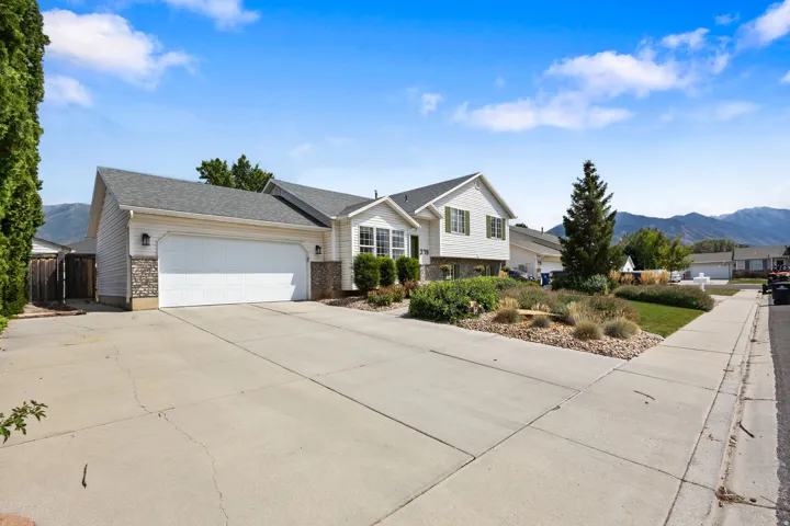 Two-car garage with white door, stone accents on exterior, and a paved driveway