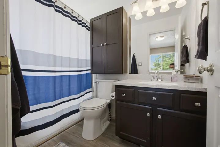 Spa-inspired bathroom featuring a dark vanity with ample storage and drawers, white quartz countertop, polished nickel fixtures, and a large illuminated mirror