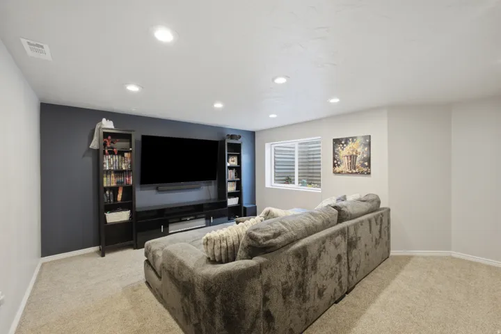 Recessed ceiling lighting, contrasting accent wall, neutral carpet flooring, and a single window with a white frame