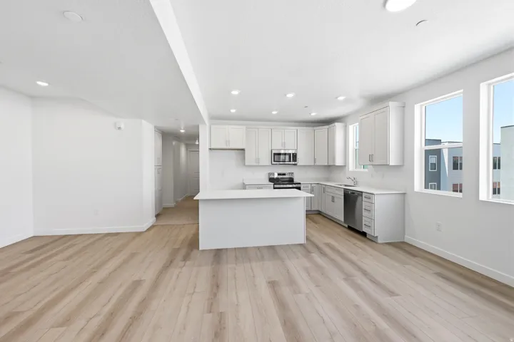 Open concept living space featuring wood-finish flooring, recessed lighting, and multiple windows