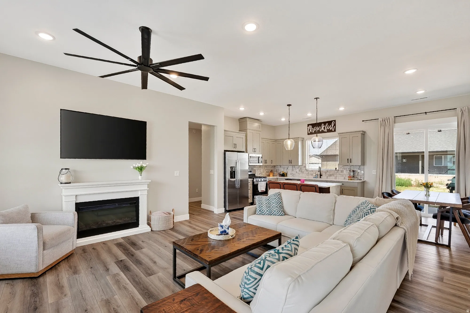 Open-concept living area with wood-finish flooring, recessed lighting, and a modern fireplace with a white mantel