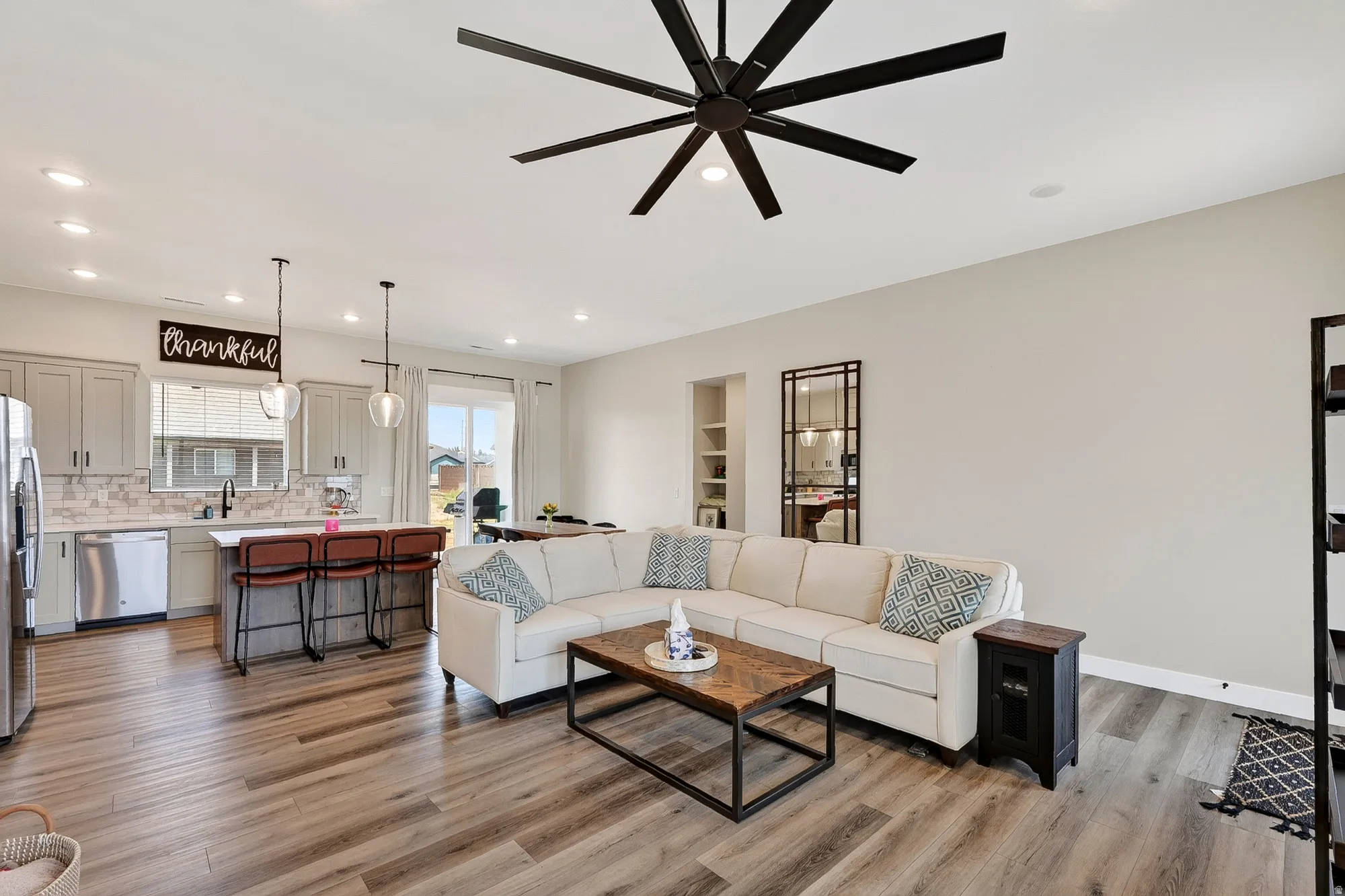 Open-concept living space featuring wood-finish flooring, recessed lighting, and a large ceiling fan
