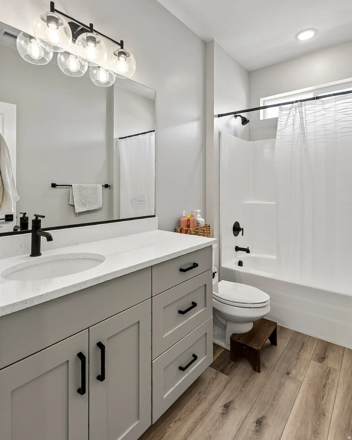 Light gray vanity with black hardware, white countertop, and integrated sink