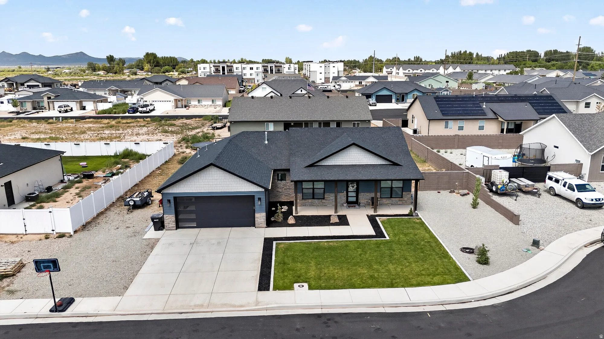 Modern exterior featuring a dark gray garage door, a prominent front lawn, a concrete driveway, and a covered entry