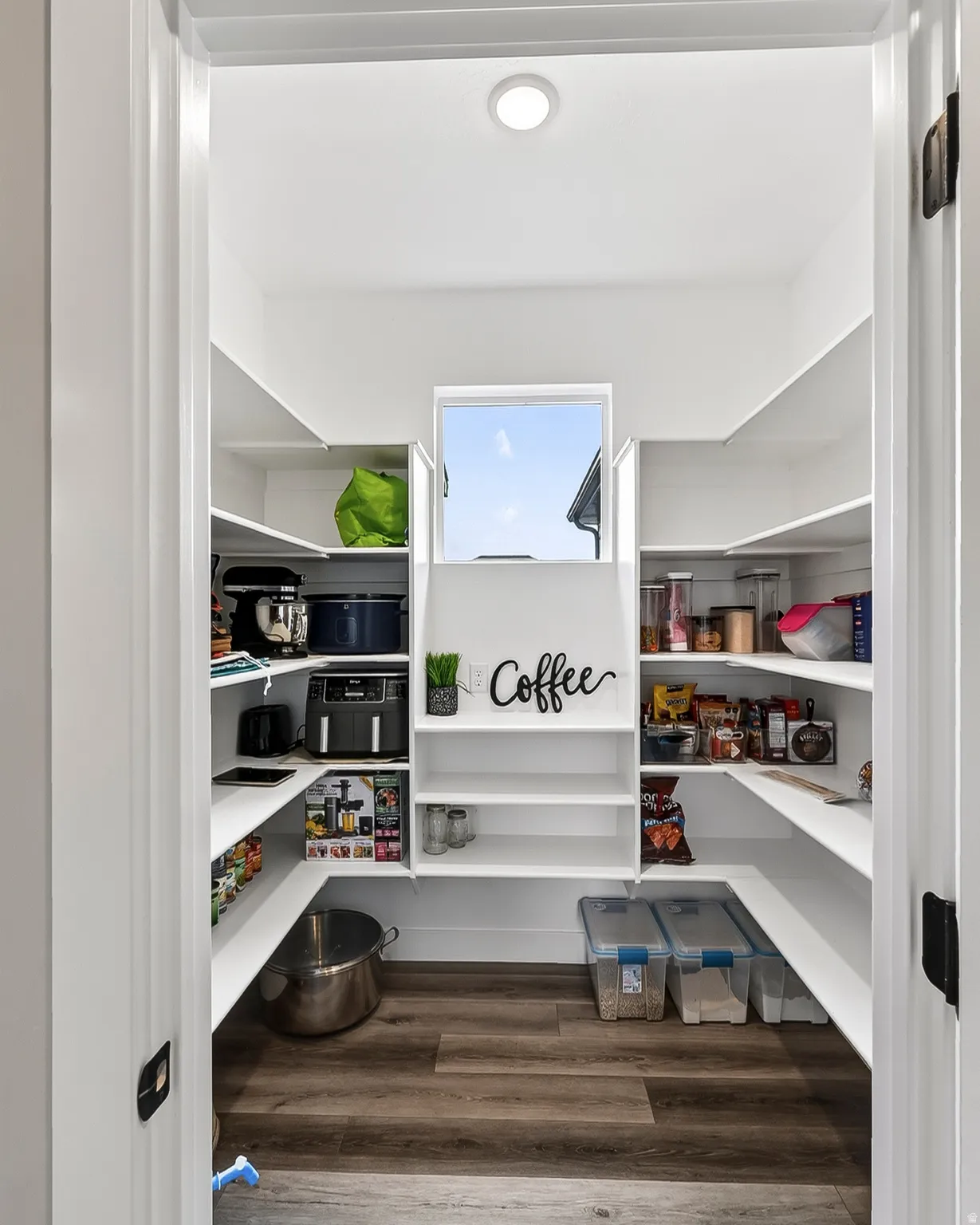 Walk-in pantry featuring extensive built-in shelving, wood-finish flooring, and a recessed ceiling light