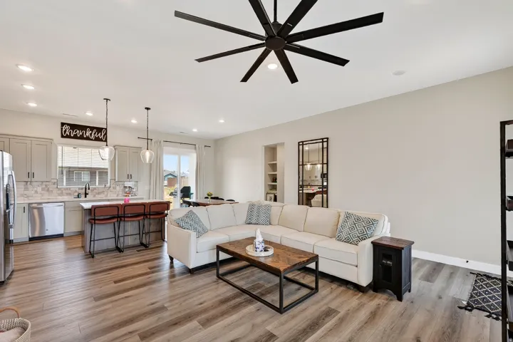 Open-concept living space featuring wood-finish flooring, recessed lighting, and a large ceiling fan