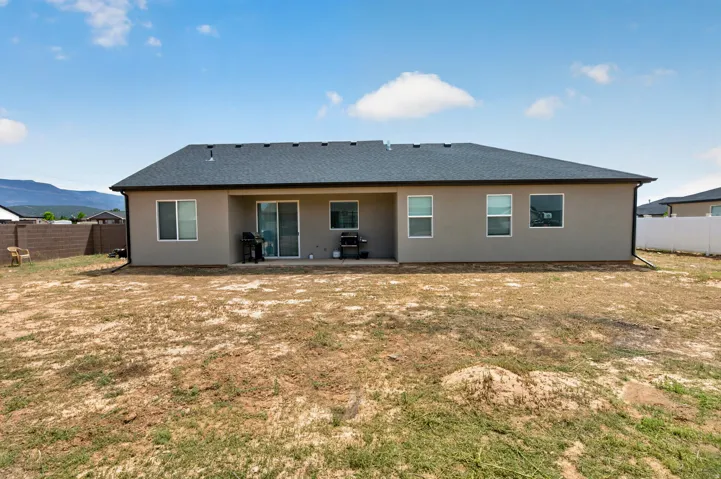 Rear exterior with a covered patio, sliding glass door, multiple windows, and a dark shingle roof