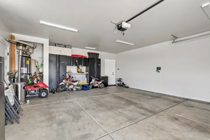 Spacious garage with a concrete floor, built-in overhead lighting, and an automatic garage door opener