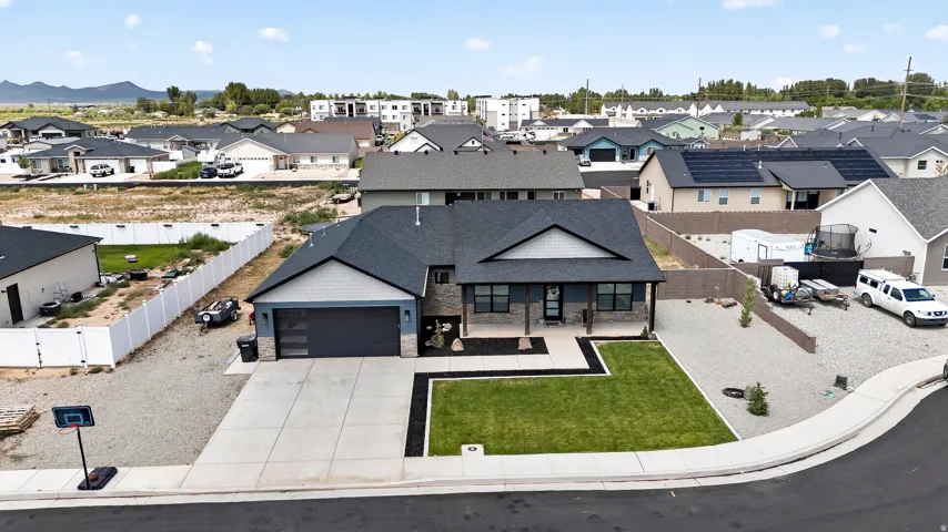 Modern exterior featuring a dark gray garage door, a prominent front lawn, a concrete driveway, and a covered entry