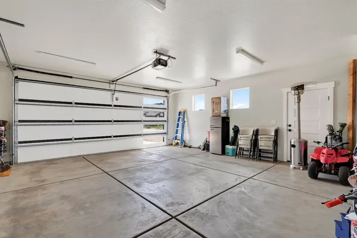 Spacious garage featuring a concrete floor, overhead lighting, multiple windows, and an insulated garage door with windows