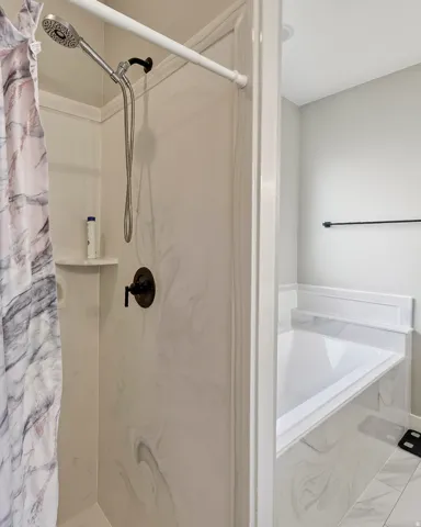 Walk-in shower with a handheld showerhead and bronze fixtures