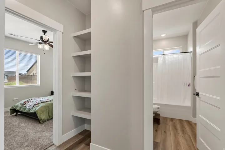 Built-in shelving, wood-finish flooring, recessed lighting, ceiling fan with light fixture, and large windows