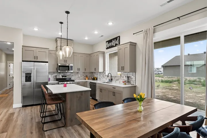 Modern kitchen featuring light wood-finish flooring, stainless steel appliances, a center island with a white countertop, and sliding glass doors