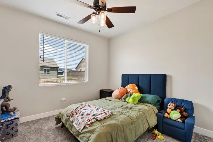 Bedroom featuring light gray walls, gray carpet, a ceiling fan with light fixture, and a window with blinds