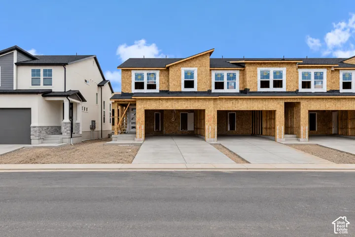 New construction homes with unfinished exteriors, multiple garages, and concrete driveways