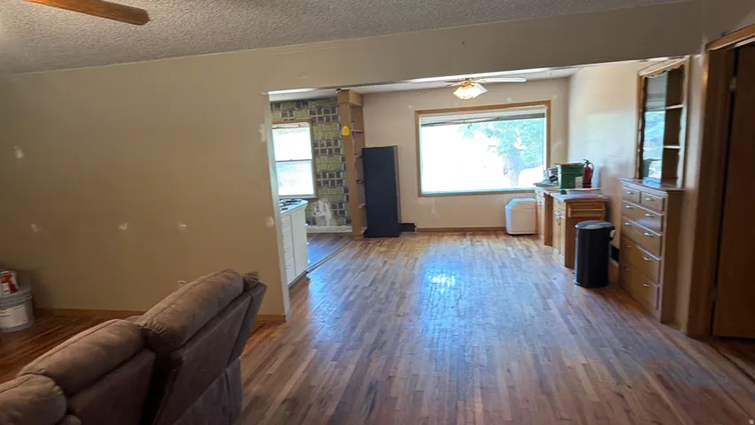 Wood-finish flooring throughout the open space, featuring a window with natural light, and a built-in wood-finish cabinet with glass doors