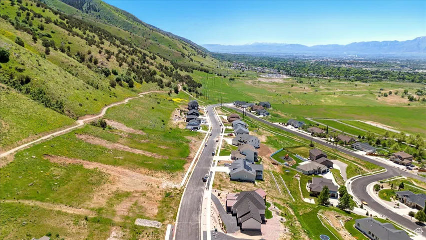 Expansive mountain backdrop with a paved road, scattered residences, and distant urban elements