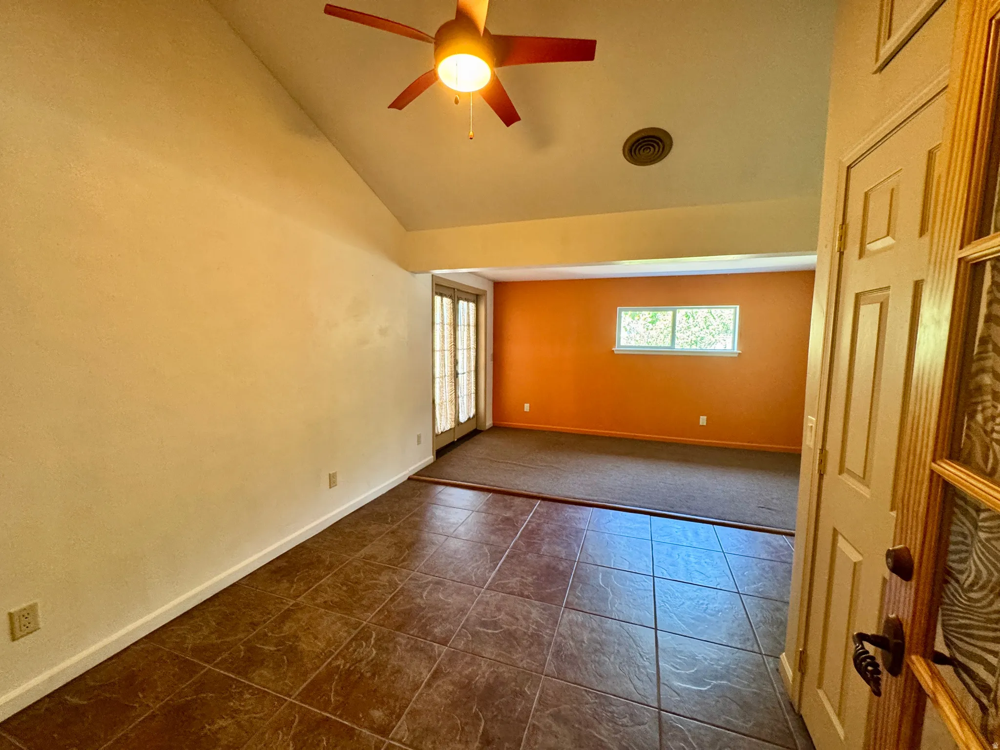 Vaulted ceiling, ceiling fan, tile flooring, glass-paneled double doors, interior window