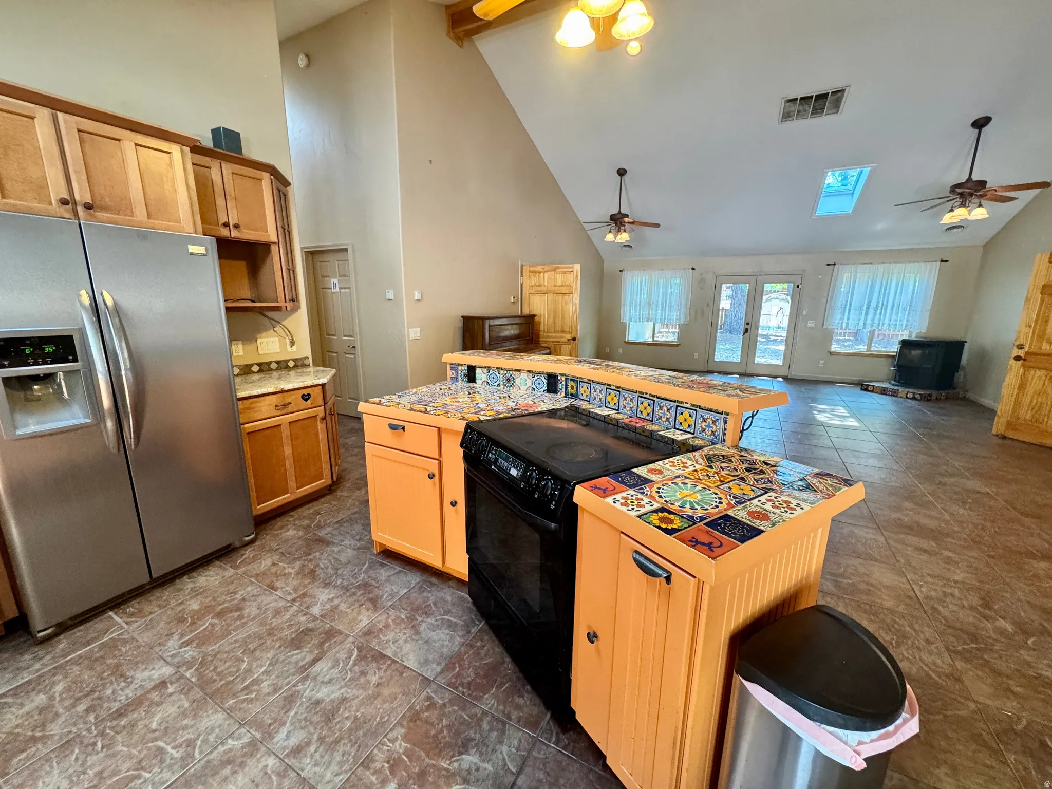 Kitchen featuring wood cabinetry, stainless steel refrigerator, and tiled countertops