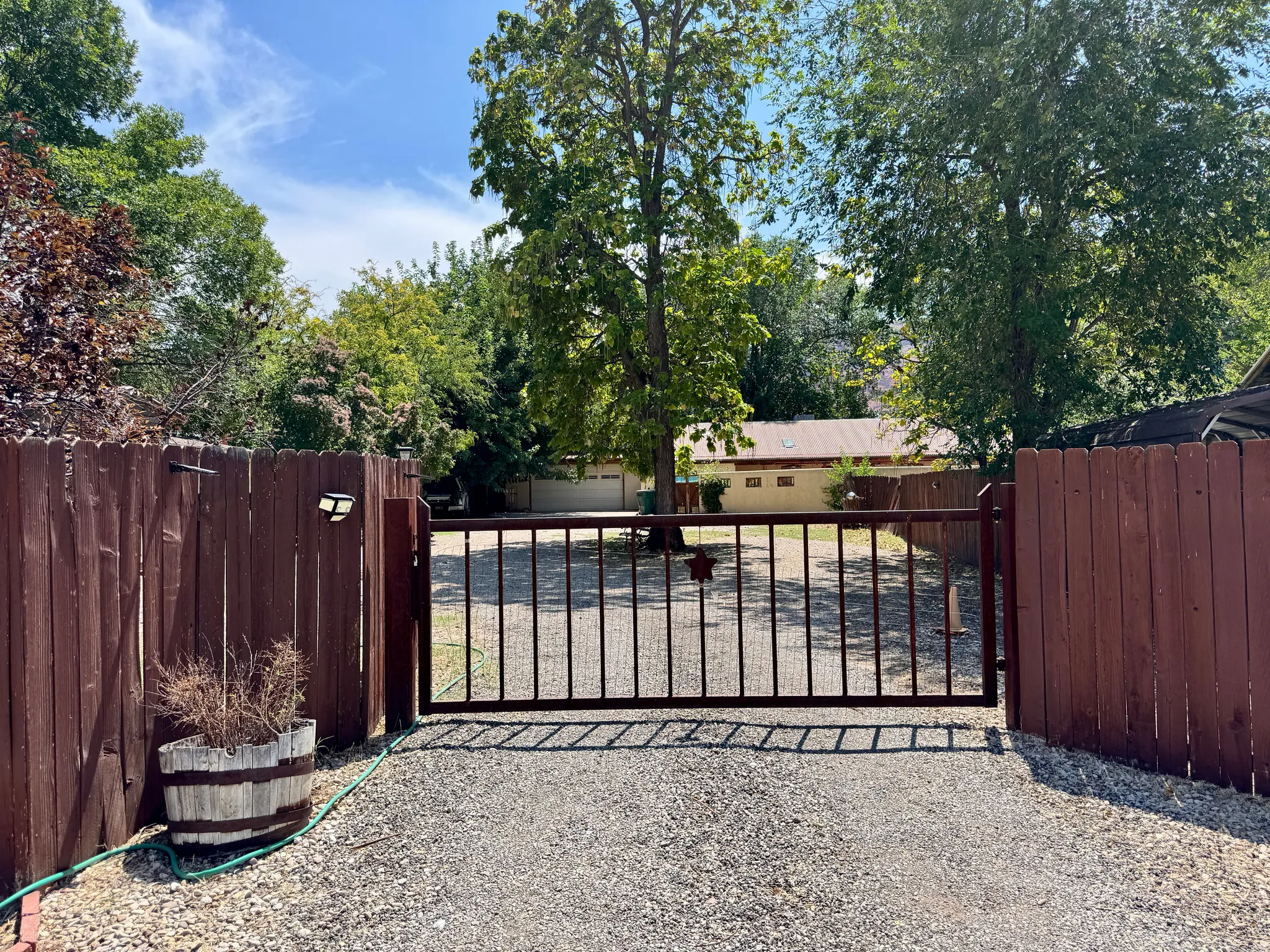 Gated entry with a wood privacy fence and a gravel driveway