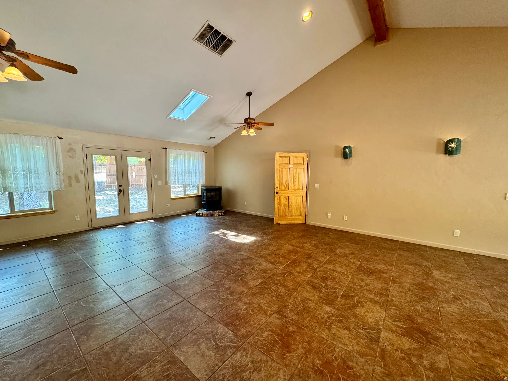 Vaulted ceiling, exposed wood beam, skylight, tile flooring, and double French doors to the exterior