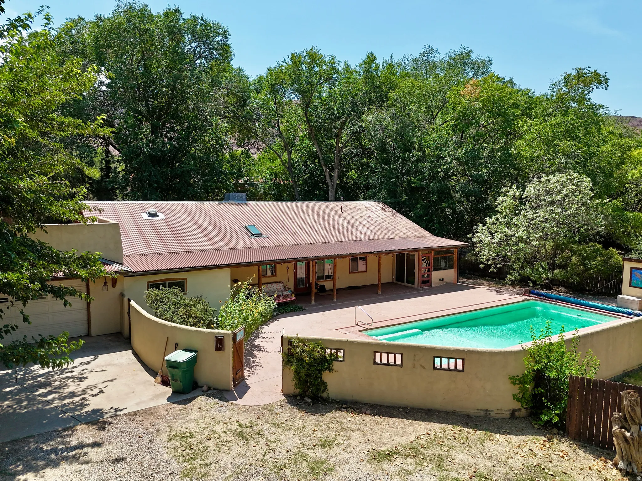 Stucco exterior with an attached garage, covered patio, and a corrugated metal roof