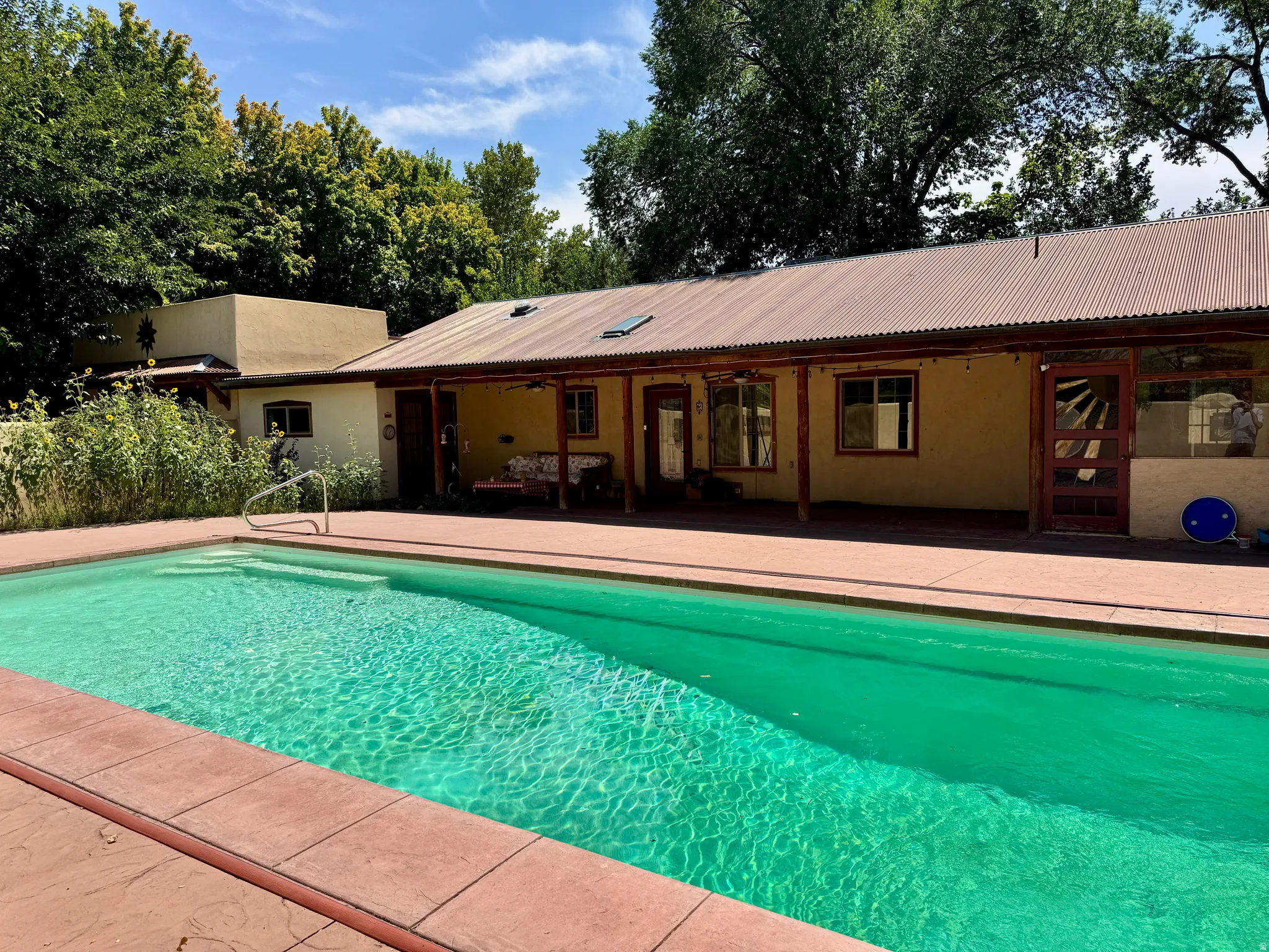 Rectangular swimming pool with integrated steps, surrounded by a red-toned paver deck