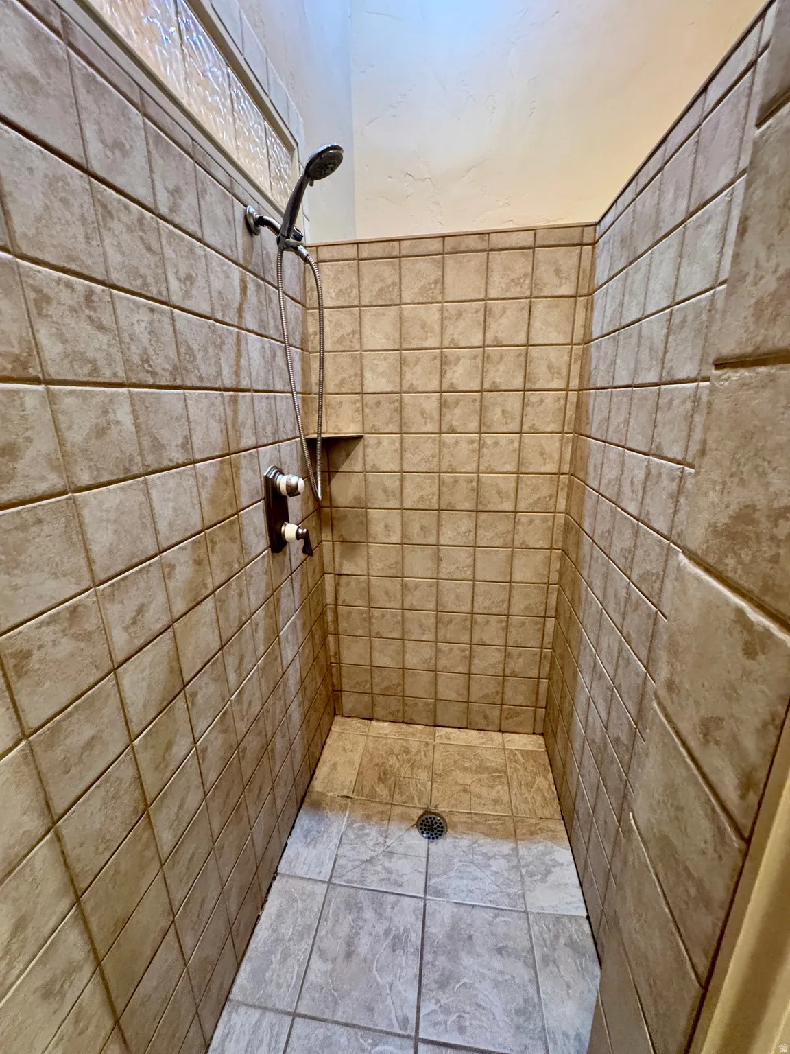Tile-surround shower with a built-in niche, handheld shower fixture, and a tiled floor