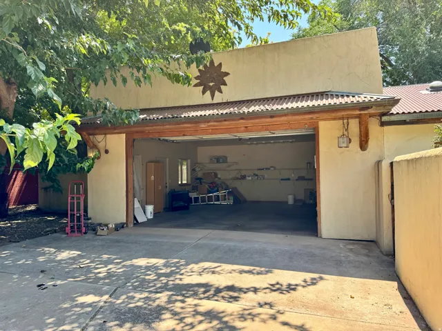 Concrete driveway leading to a two-car garage with a corrugated metal roof