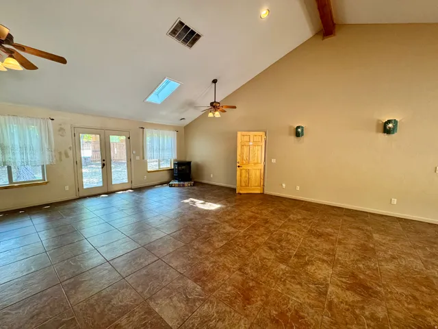Vaulted ceiling, exposed wood beam, skylight, tile flooring, and double French doors to the exterior