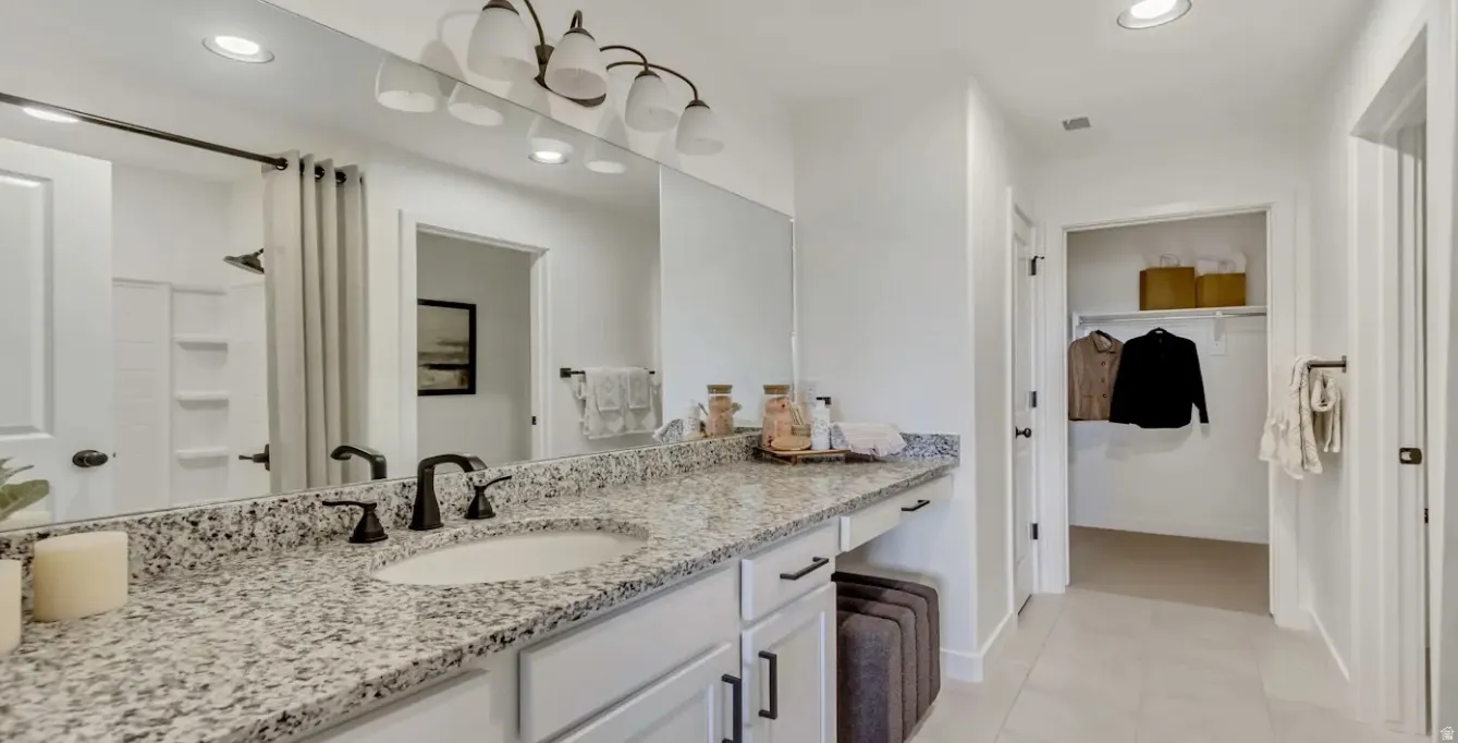 Dual vanity with granite countertop, integrated sink, and dark bronze fixtures. This home is under construction. Pictures are of a similar home.