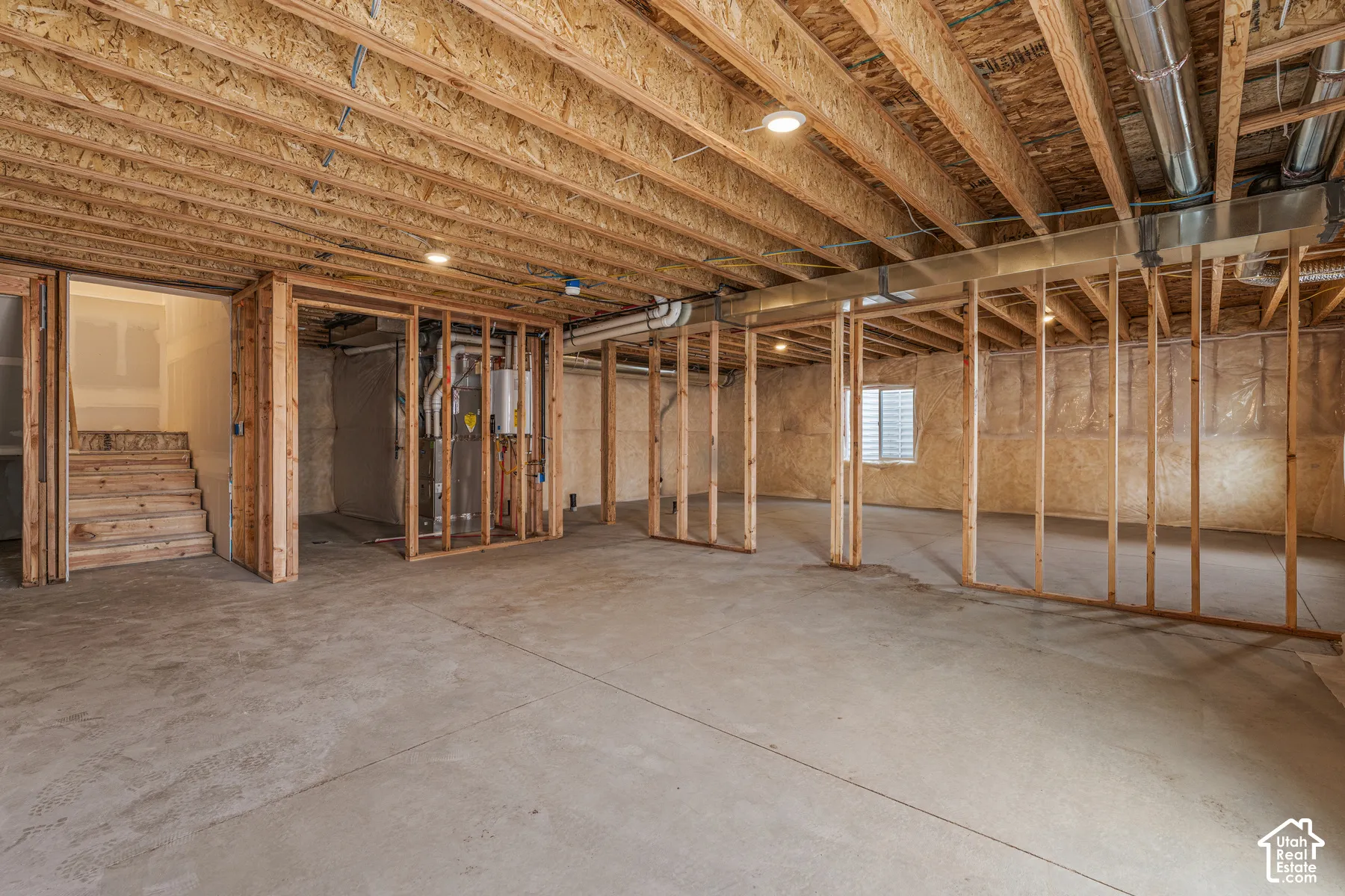Unfinished basement featuring concrete flooring, exposed wood framing, recessed lighting, and a visible window