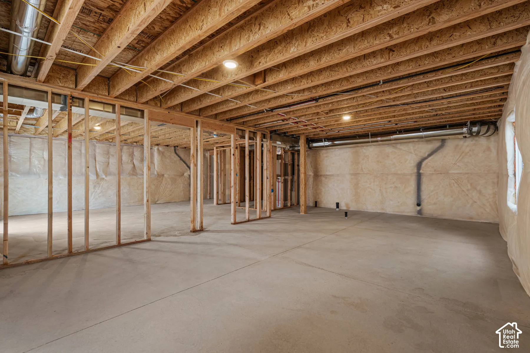 Unfinished basement with concrete flooring and exposed wood framing