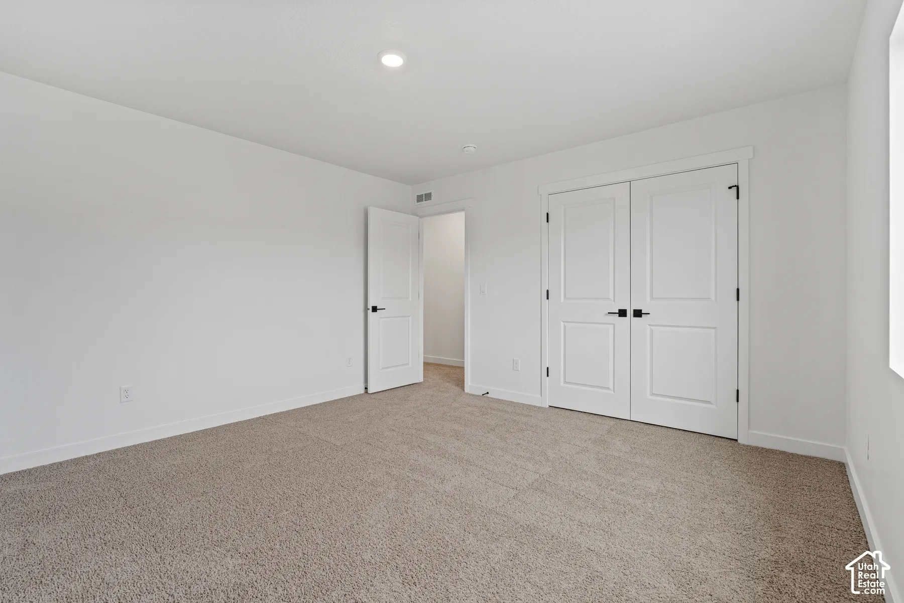 Plush carpeting, recessed ceiling lighting, a white painted interior, and paneled doors with dark hardware