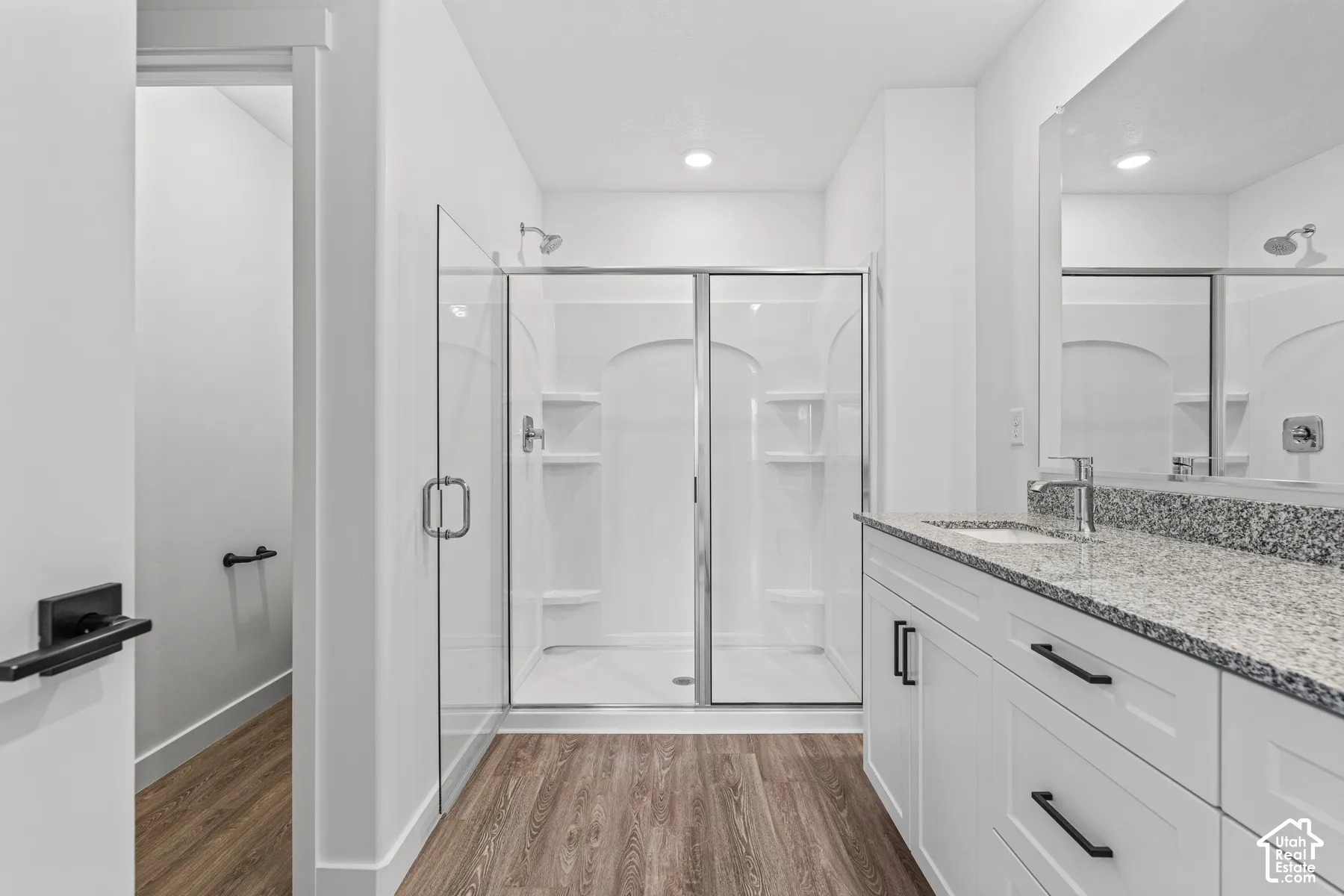 White vanity with a speckled countertop, undermount sink, and chrome faucet