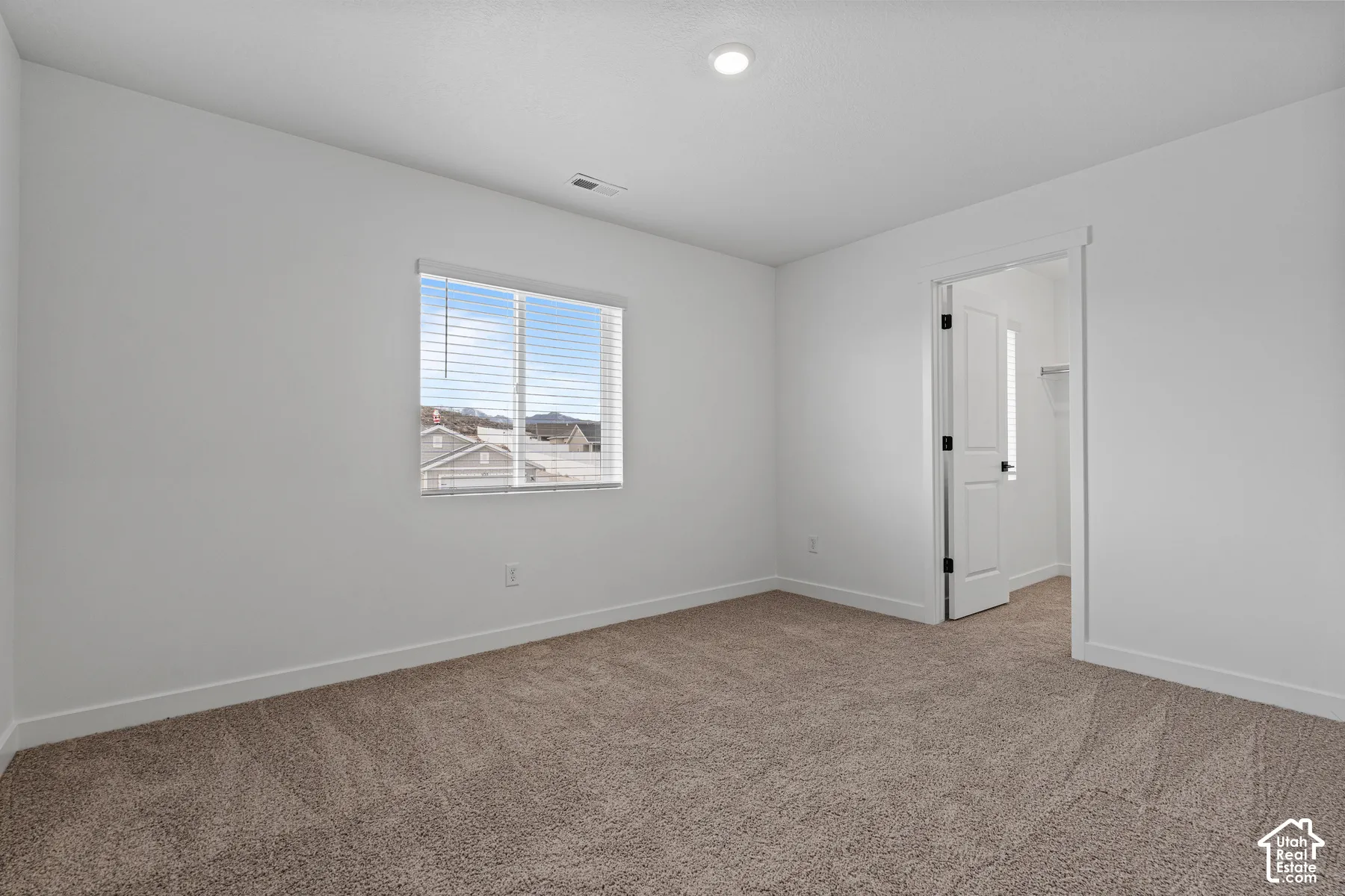 Plush carpeted flooring, a recessed ceiling light, and a white interior door with black hardware