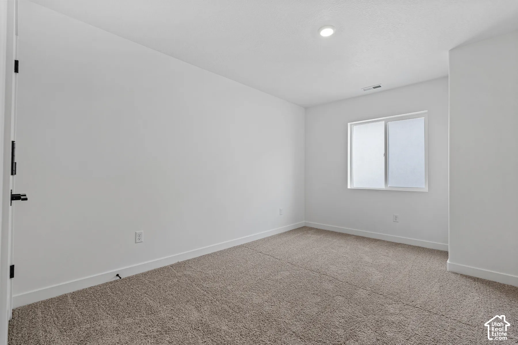 Recessed ceiling lighting, white walls, and neutral carpeting