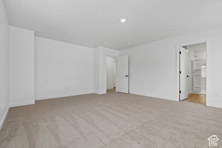 Expansive carpeted room featuring a white interior and recessed lighting