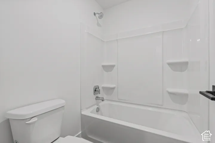 White bathtub with a chrome shower head, chrome faucet, and integrated shelving