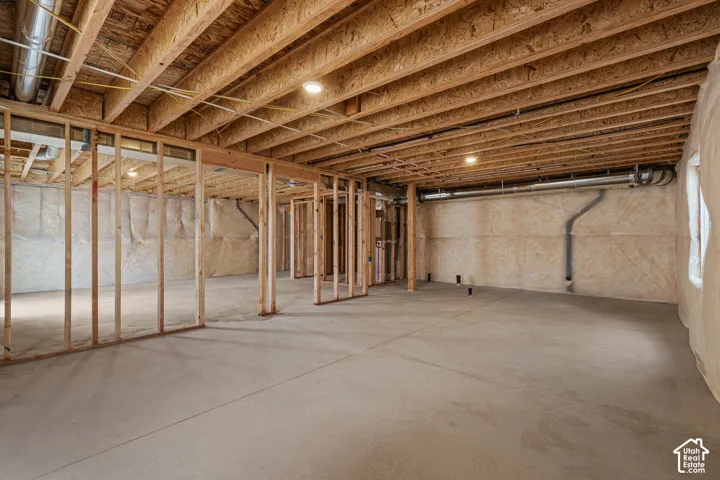 Unfinished basement with concrete flooring and exposed wood framing