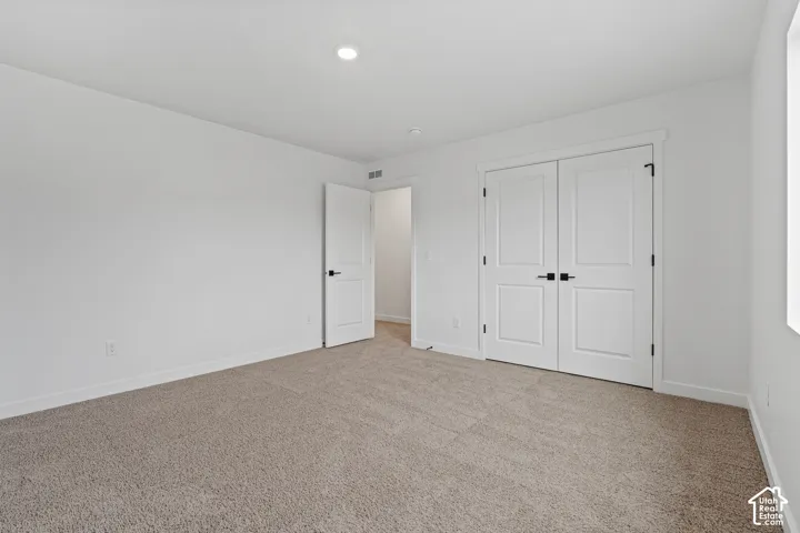 Plush carpeting, recessed ceiling lighting, a white painted interior, and paneled doors with dark hardware
