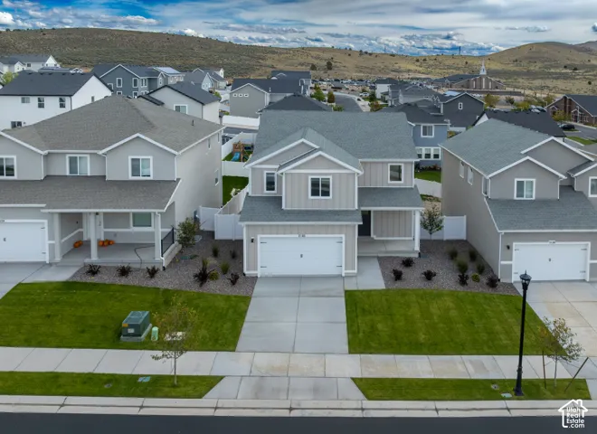 Two-story exterior with a covered entry, attached garage, concrete driveway, and landscaped front yard with a manicured lawn