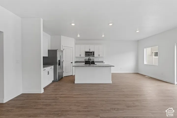 Open-concept living space featuring wood-finish flooring, recessed lighting, and a kitchen island with stone countertops