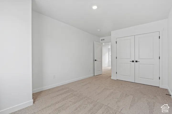 Recessed ceiling lighting, white walls, carpeted flooring, and a double-door closet with matte black hardware