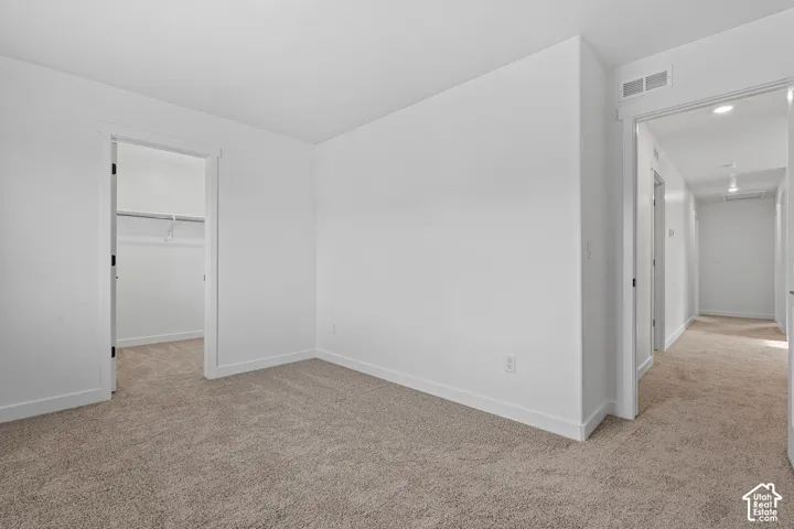 Neutral color palette with white walls, plush carpeting, and recessed lighting in the hallway
